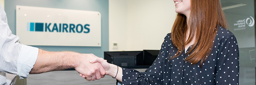 image of two people shaking hands with office in the background