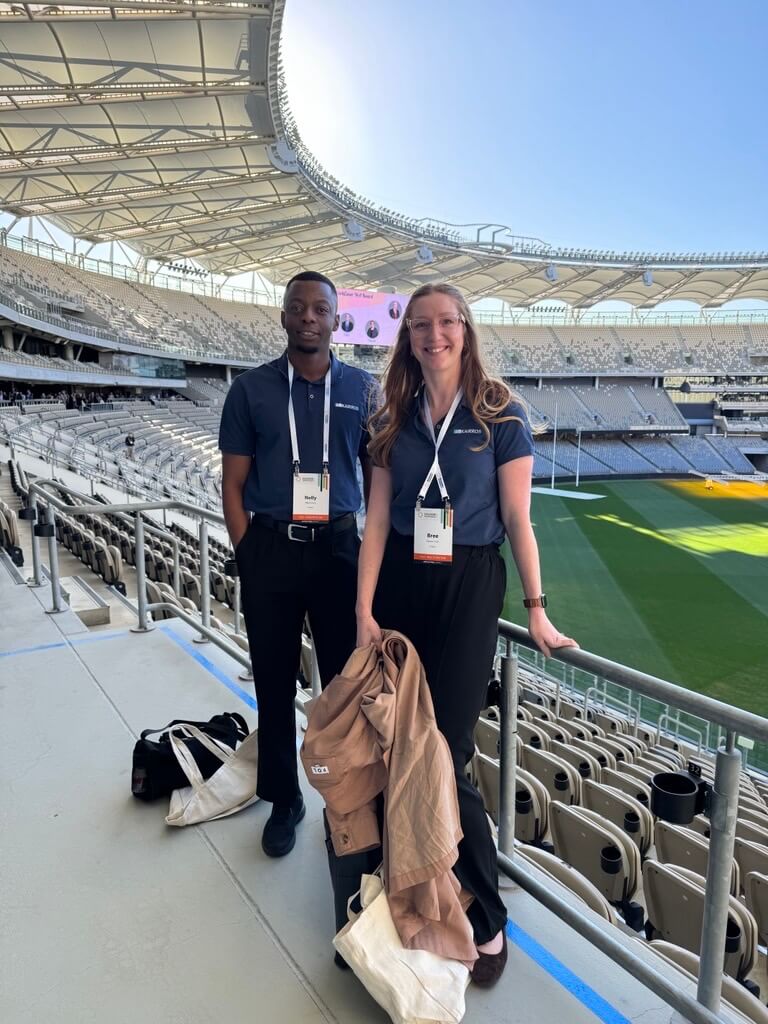 Two people in a stadium smiling to camera