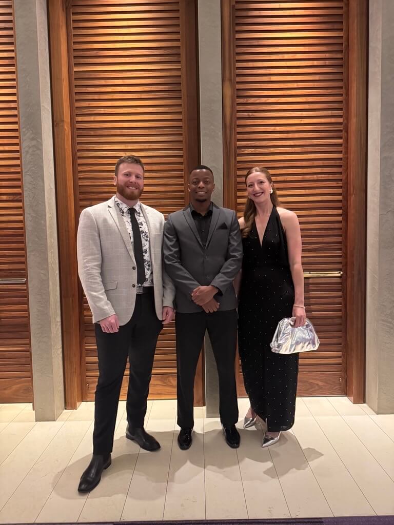 Three people in formal wear smiling to camera