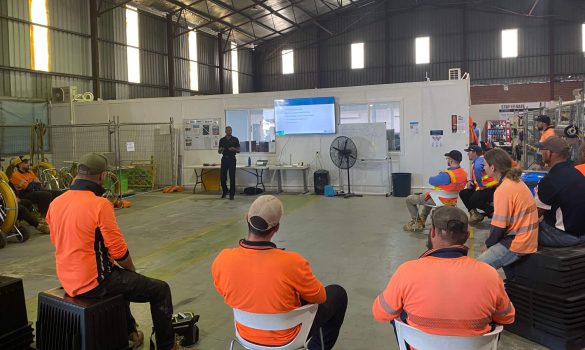 A group of people in a Warehouse watching a presentation